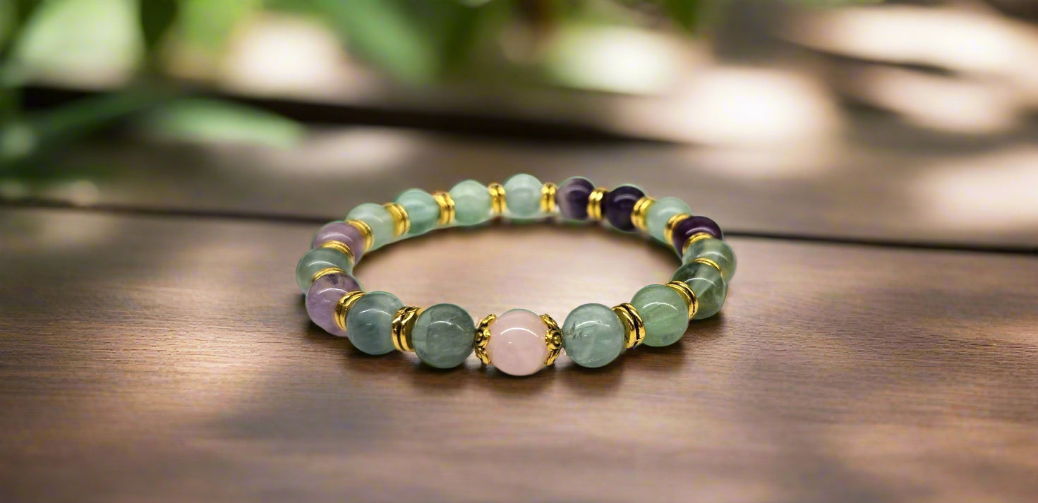Multicolored beaded bracelet on a wooden surface with blurred greenery in the background