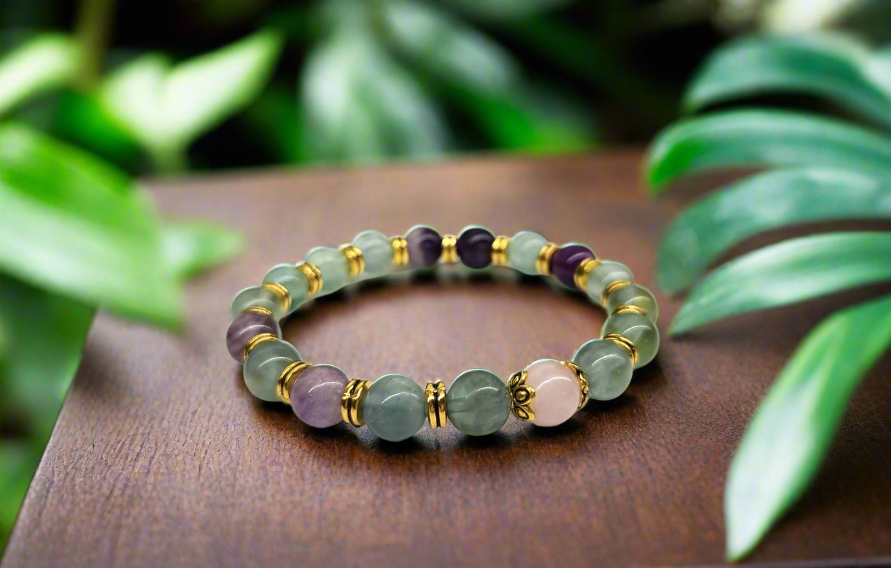 Multicolored beaded bracelet on a wooden surface with green leaves in the background